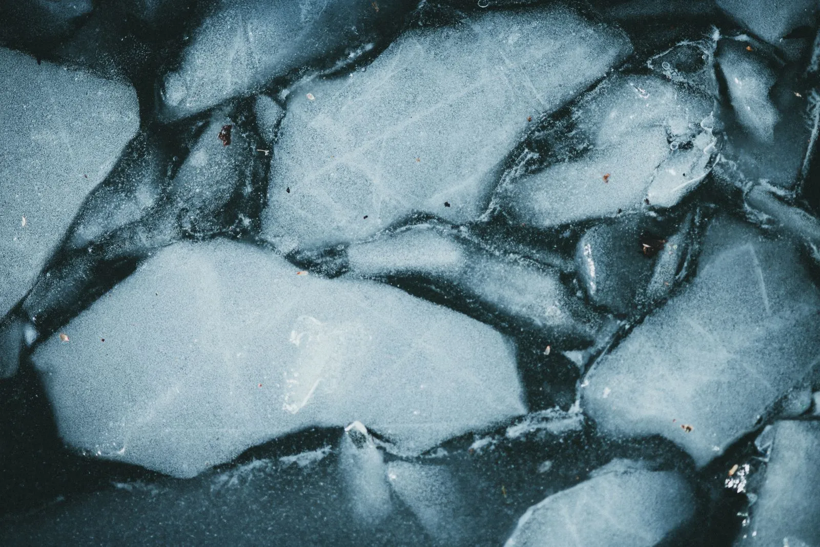 Nahaufnahme einer glatten, gefrorenen Eisfläche in kalten Blautönen.