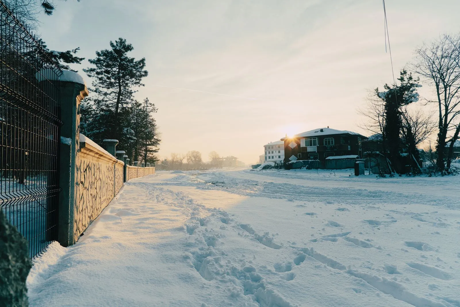 Verschneiter Gehweg mit Fußspuren im Morgenlicht eines Wintertages.